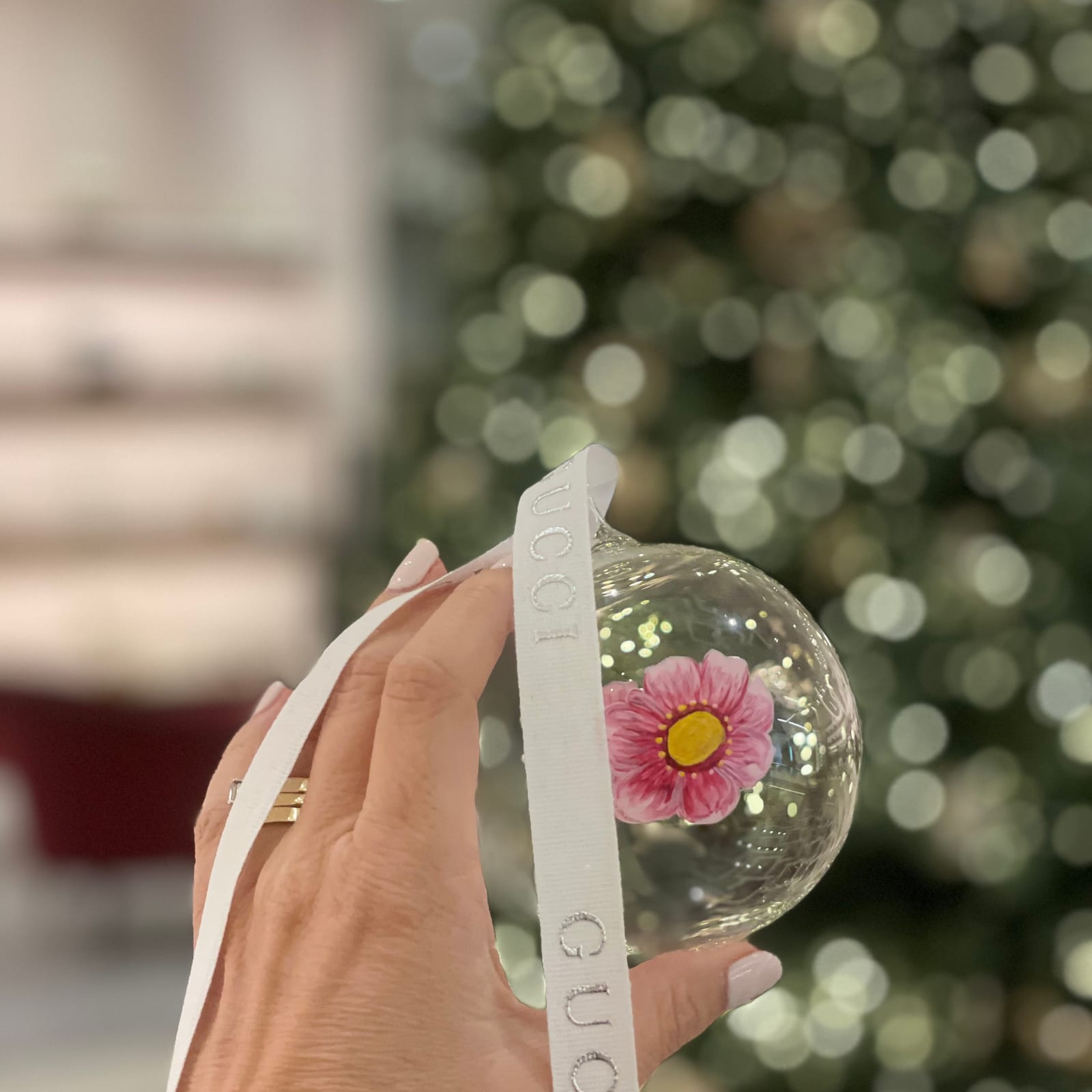 Hand-painted pink flower on a Gucci glass bauble in front of a Christmas tree