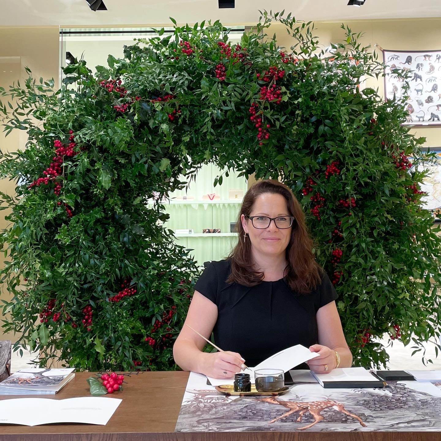 Alison writing Christmas calligraphy in front of a large wreath