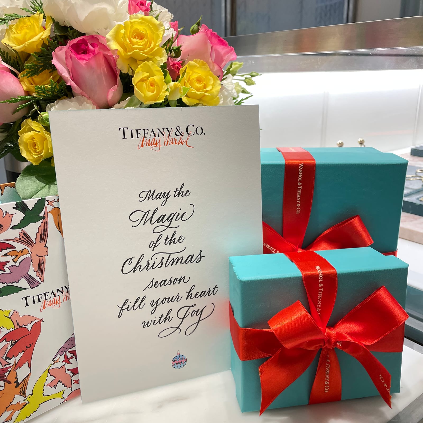 Christmas message in calligraphy on a Tiffany & Co. card beside gift boxes