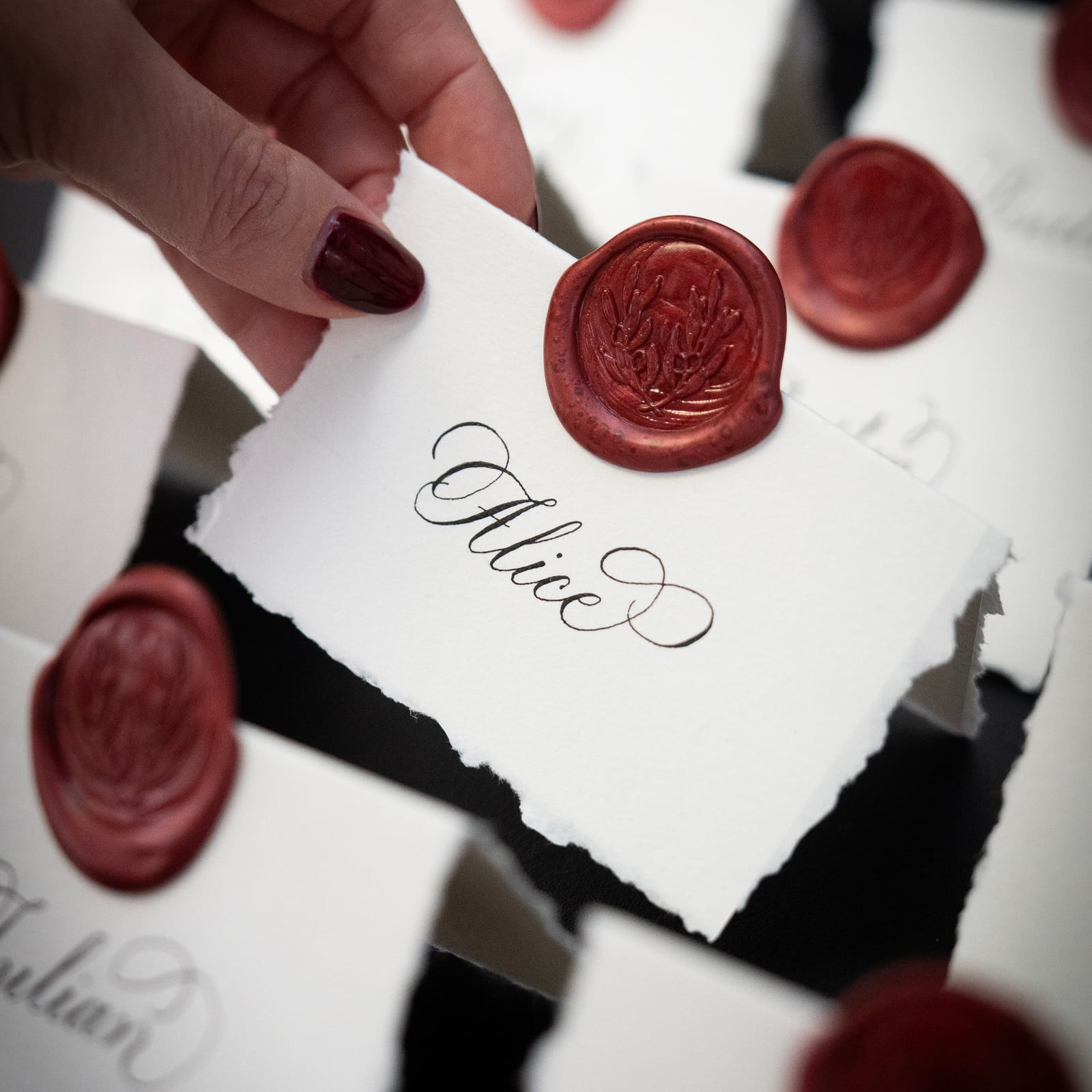 Hand torn deckled edge place cards with traditional pointed pen calligraphy and wine coloured wax seal