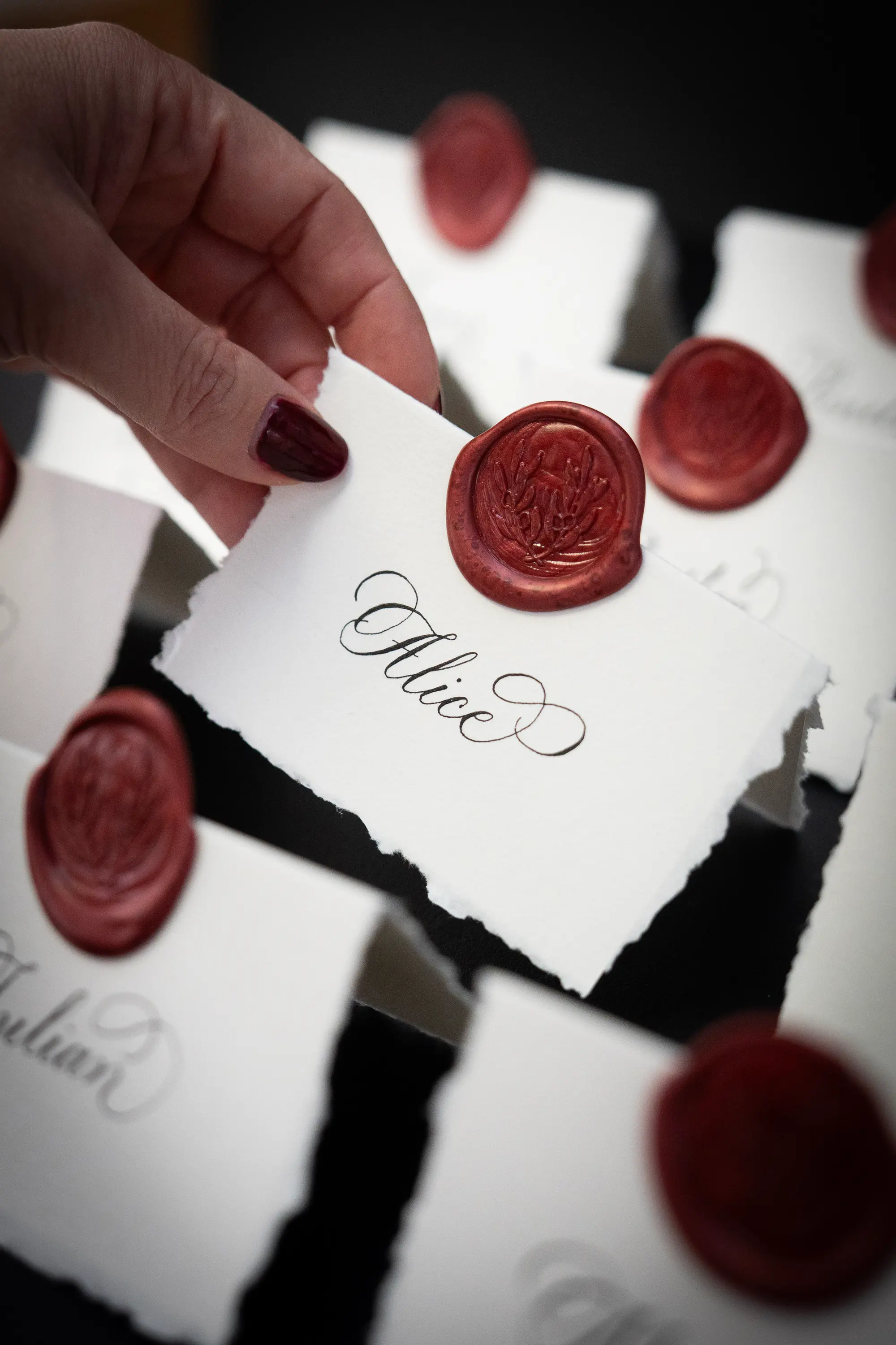Hand torn deckled edge place cards with traditional pointed pen calligraphy and wine coloured wax seal